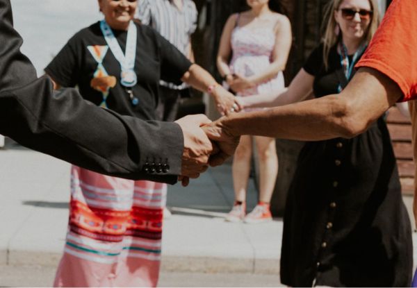 A photo of Indigenous students and family walking around in a circle and smiling.