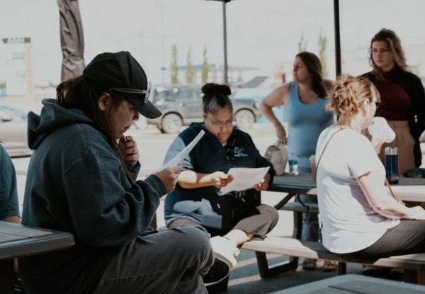 A photo of Indigenous students looking at the course materials in their hands.