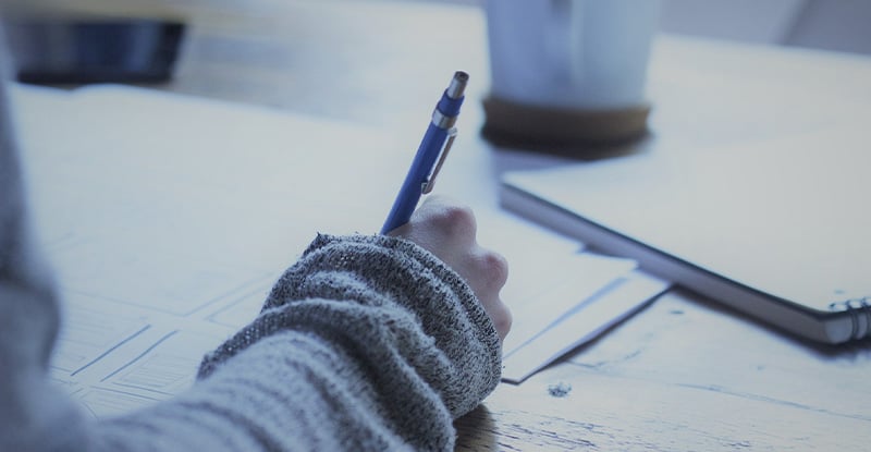 A photo of a person writing on a notebook.