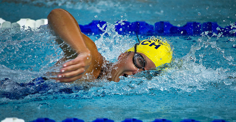 A photo of a swimmer captured mid-stroke in the water, with splashes around them.