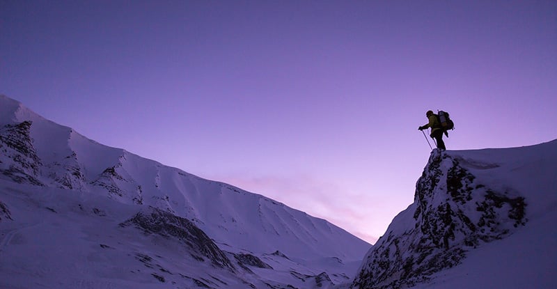 A photo of a person standing at the top of a snowy mountain.