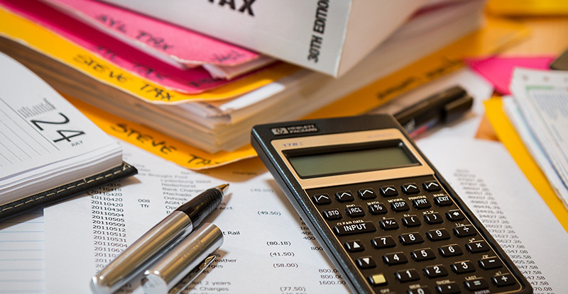 A photo of tax papers spread out on a table with a calculator placed at the top.