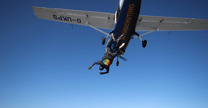 A photo of a person diving out of a small plane.