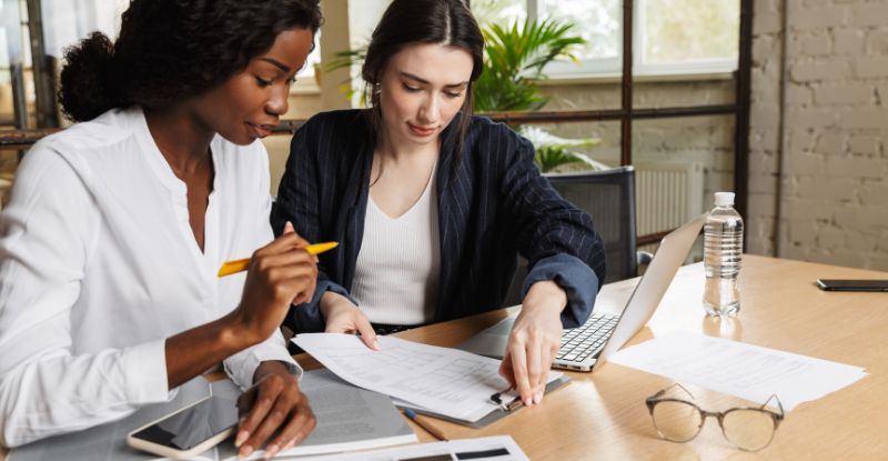 A photo of an African woman and a Caucasian woman working on a form.