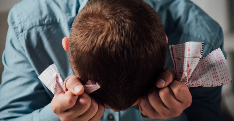 A photo of a student holding his head in his hands with crumpled scantron sheets indicates that he has been unsuccessful in the test.