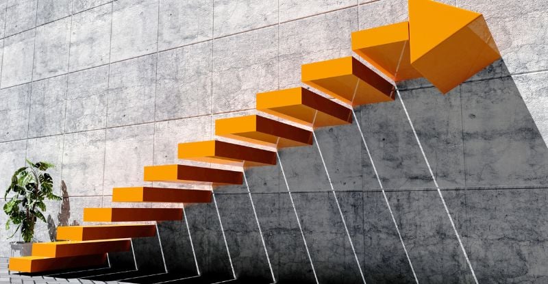 An illustration of a concrete wall with floating orange staircase with the top step ending in an arrow.