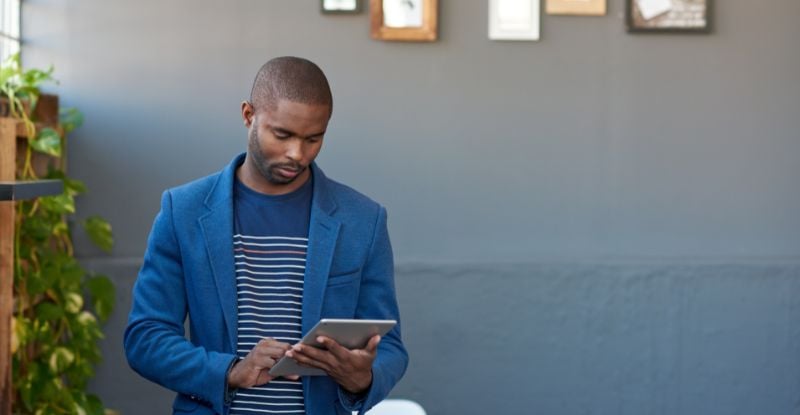 A photo of an African man looking seriously at his tablet.