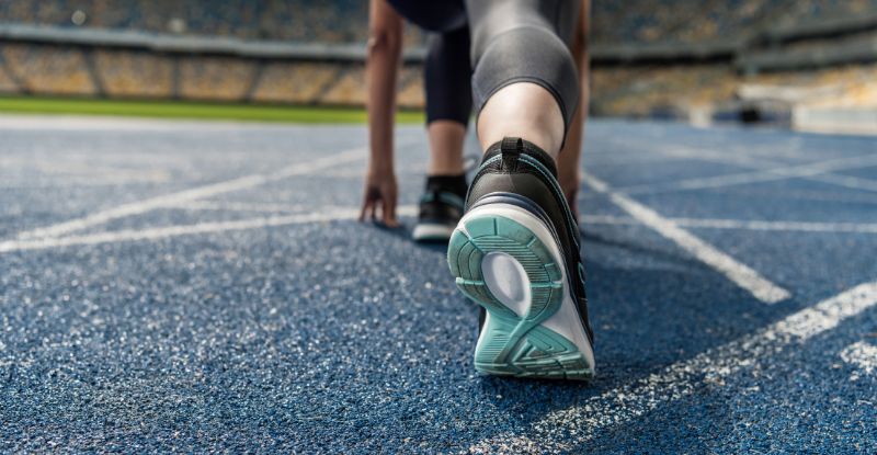 A photo taken on a running track of a runners foot from behind.