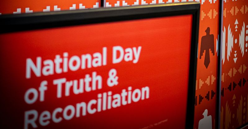 A photo of National Truth and Reconciliation Day with a background red in colour with Indigenous patterns.